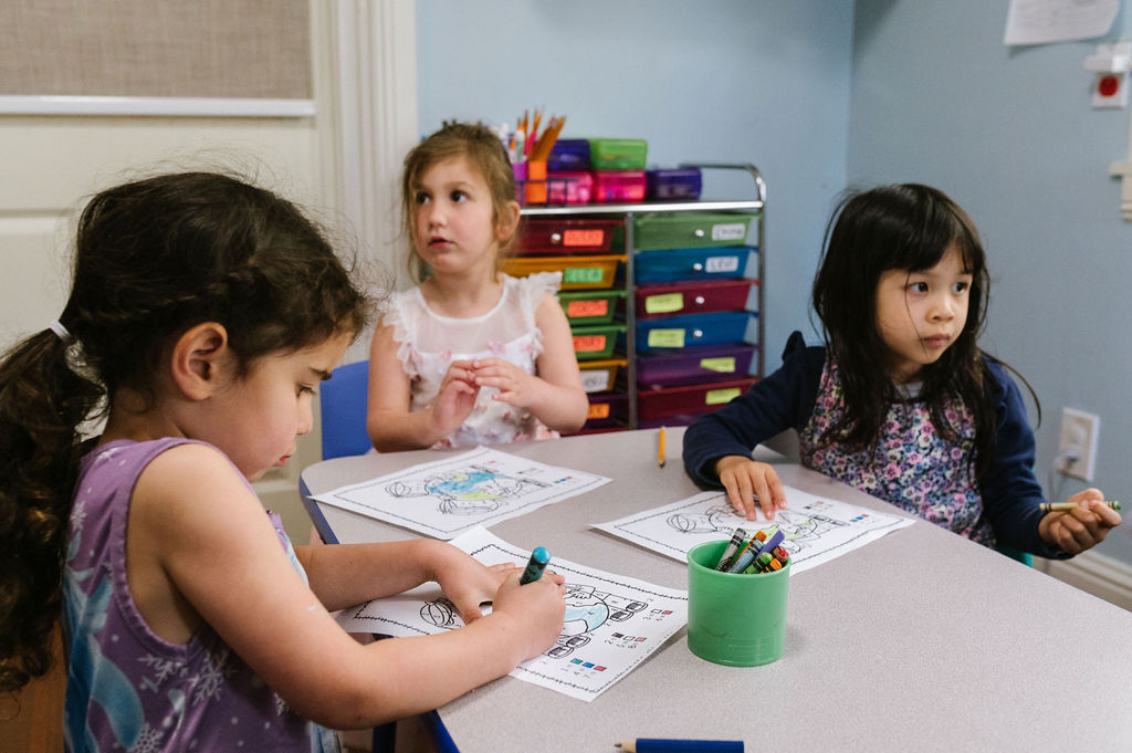 Three children siting at a classroom table.