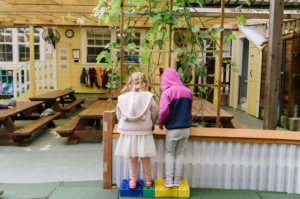 Child in pink hoodie next to another child in preschool.