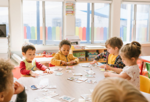 Kids at a school table playing with paper doll cards