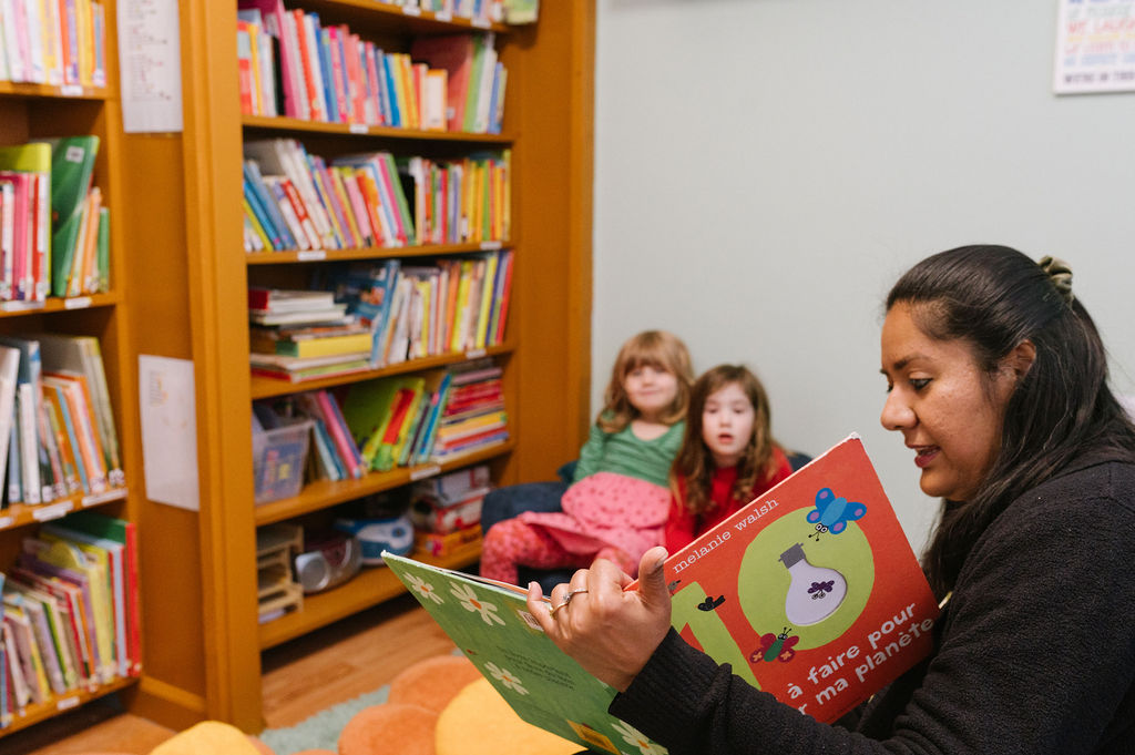 A teacher reading a book to children in French Preschool.