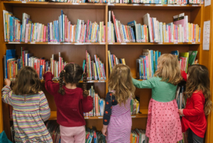 Children picking out books from a big shelf