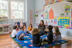 Students sitting in a circle listening to teachers lesson