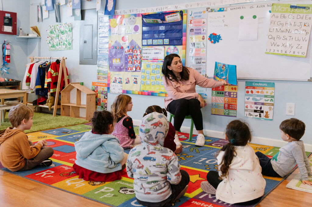Kids sitting around a teacher who is reading them a story from a book