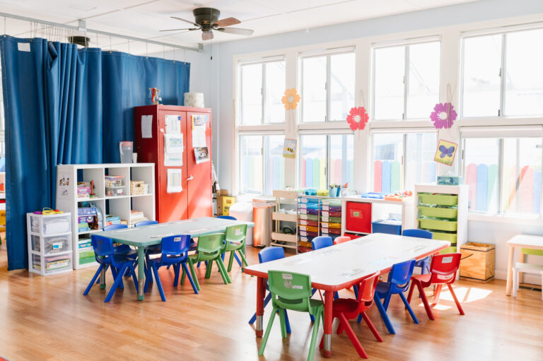 An empty preschool classroom with tables and chairs aligned neatly
