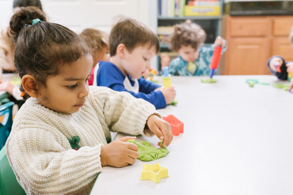 Kids playing with clay and toys at their school table