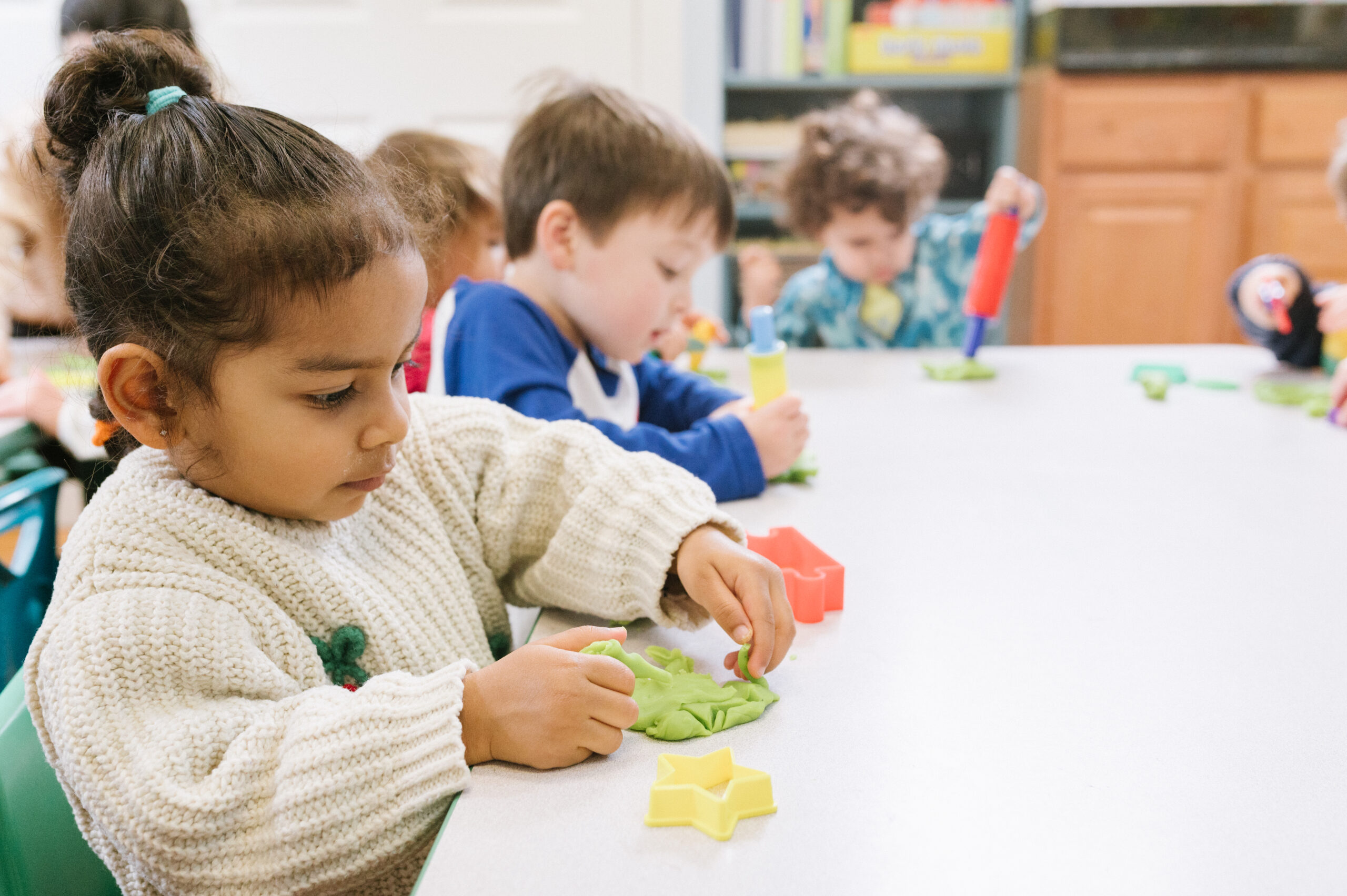 Kids playing with clay and toys at their school table