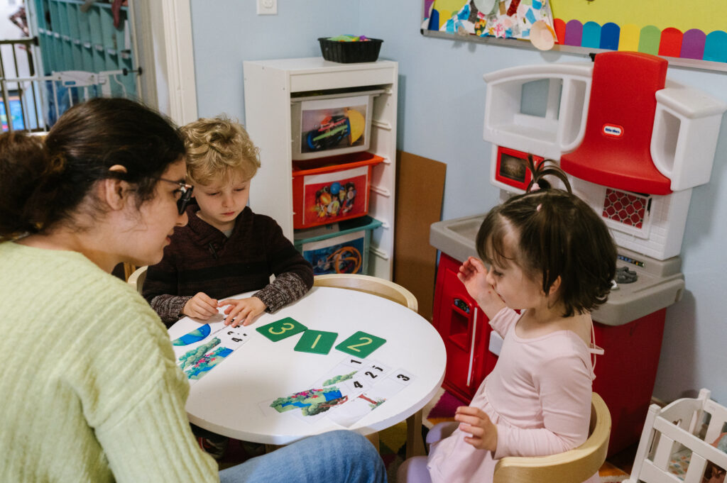 Children using number cards with their teacher