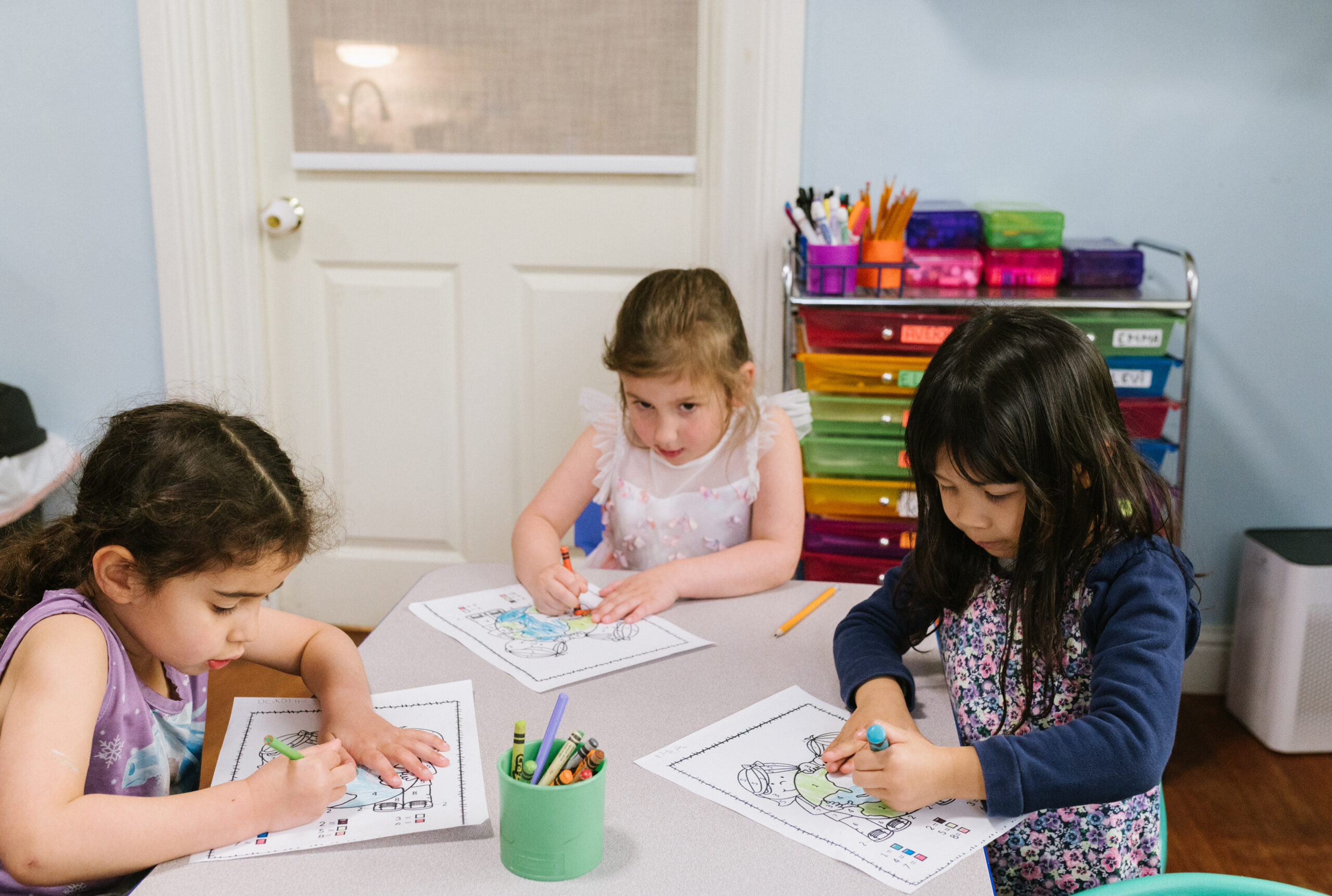 Three kids coloring at school