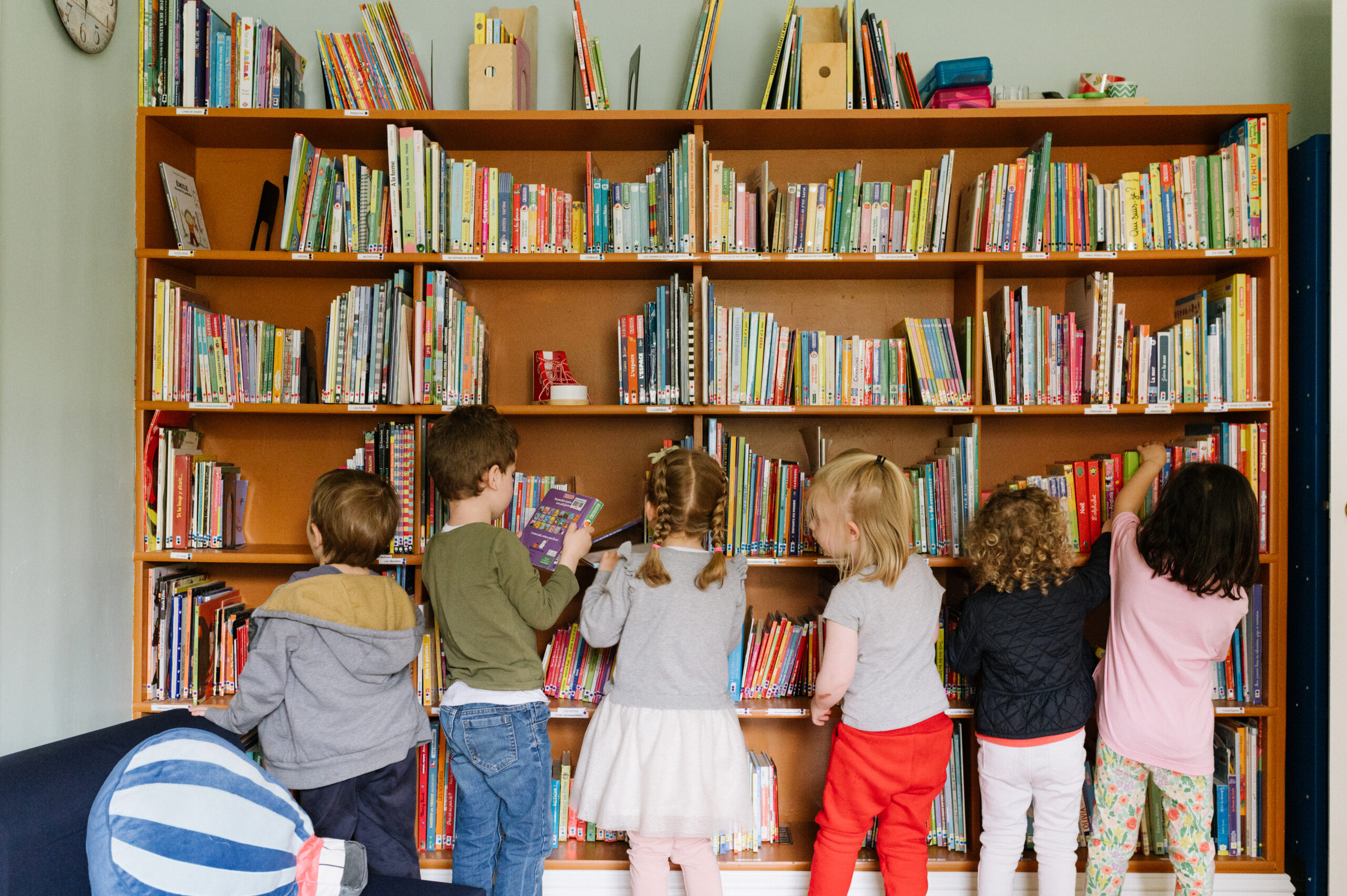 Kids looking through a big shelf of books