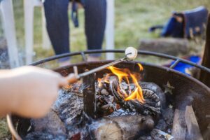 Someone holding a marshmallow over a camp fire