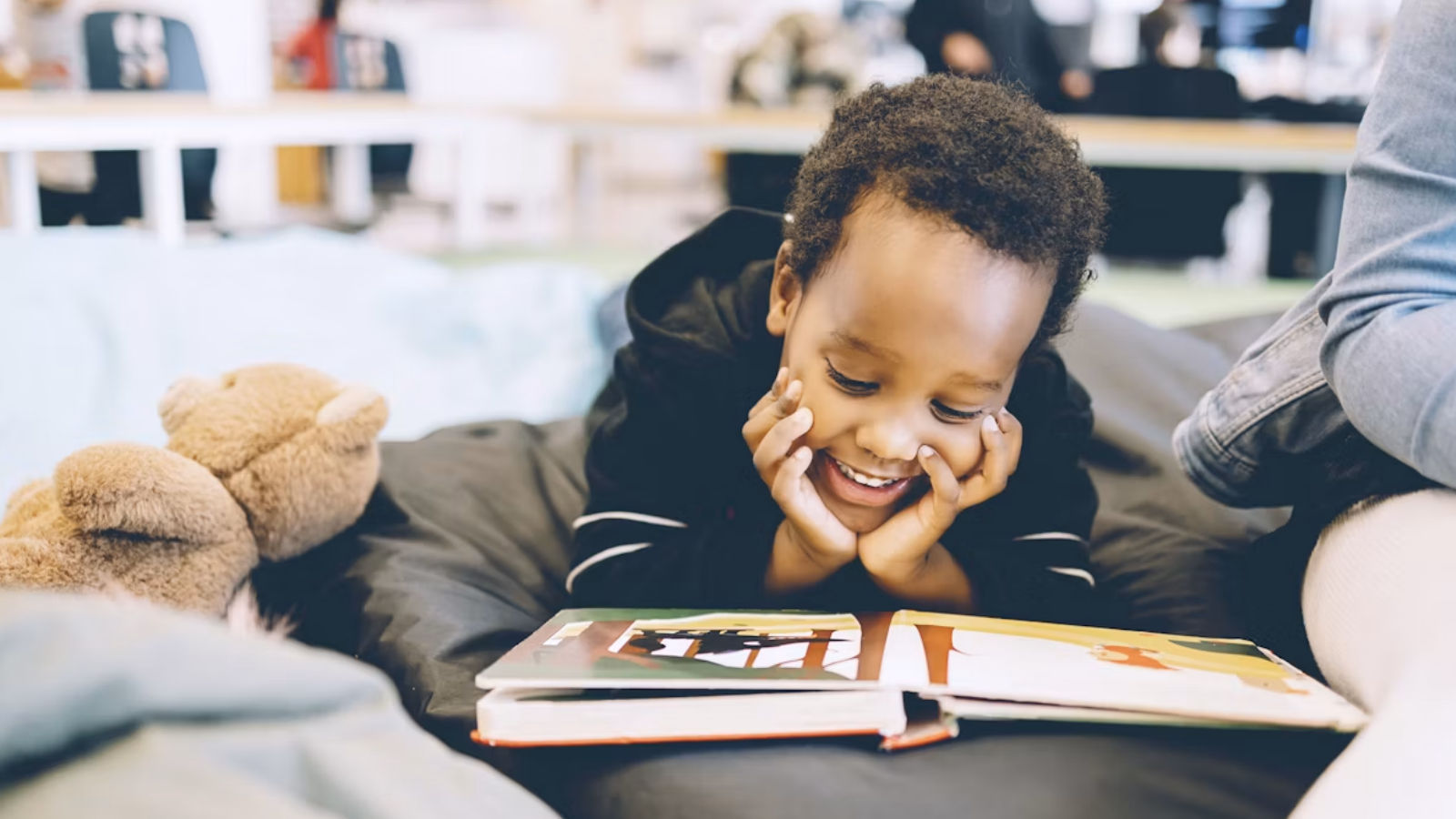 A kid smiling while they read a book 