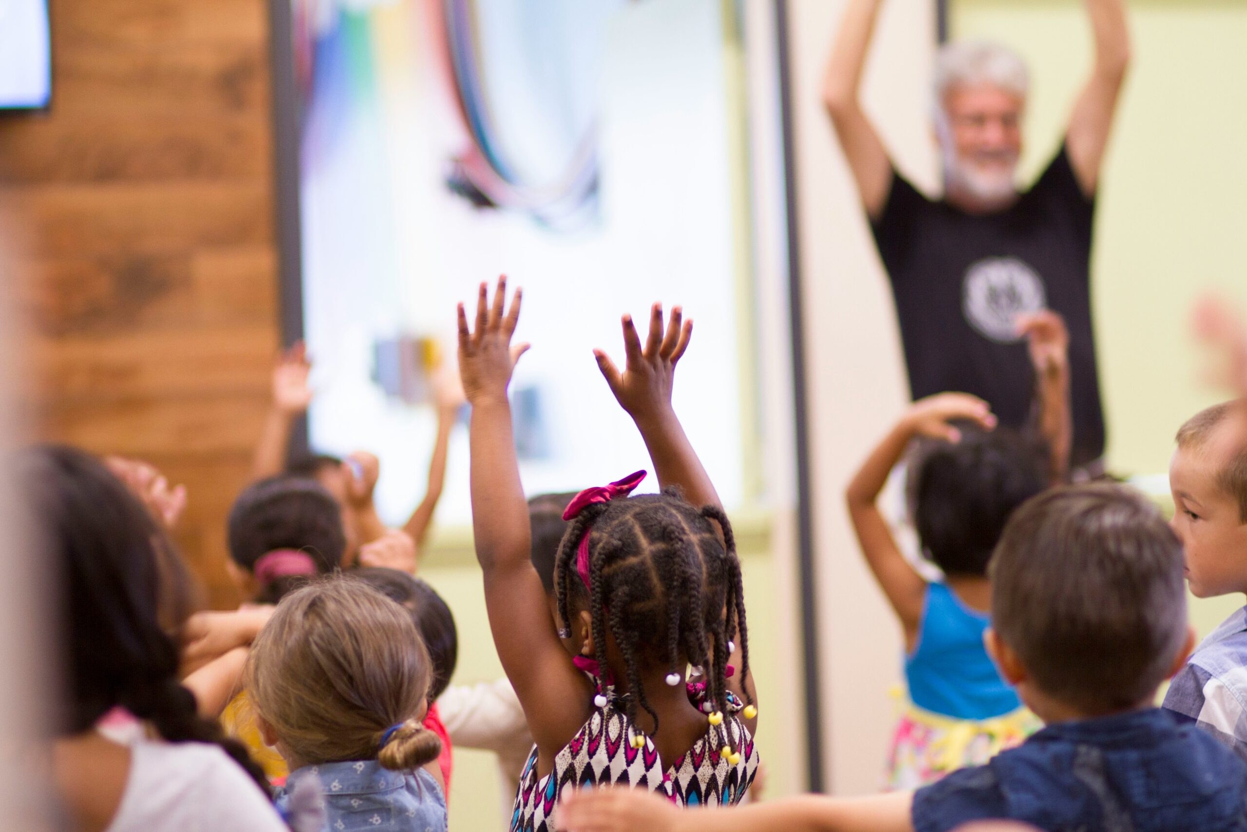 Preschoolers holding their hands up with the teacher