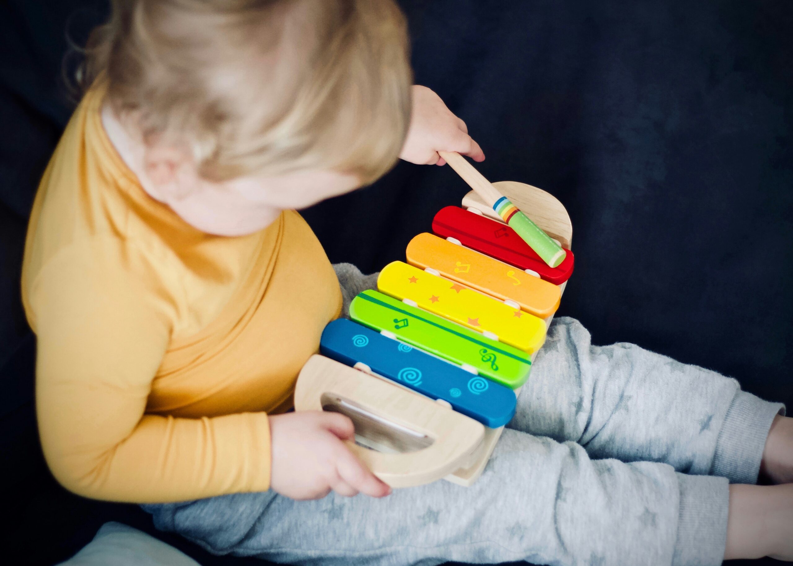 A toddler playing on a toy xylophone