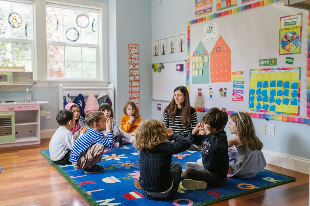 Teacher with students at ABS sitting on the floor.