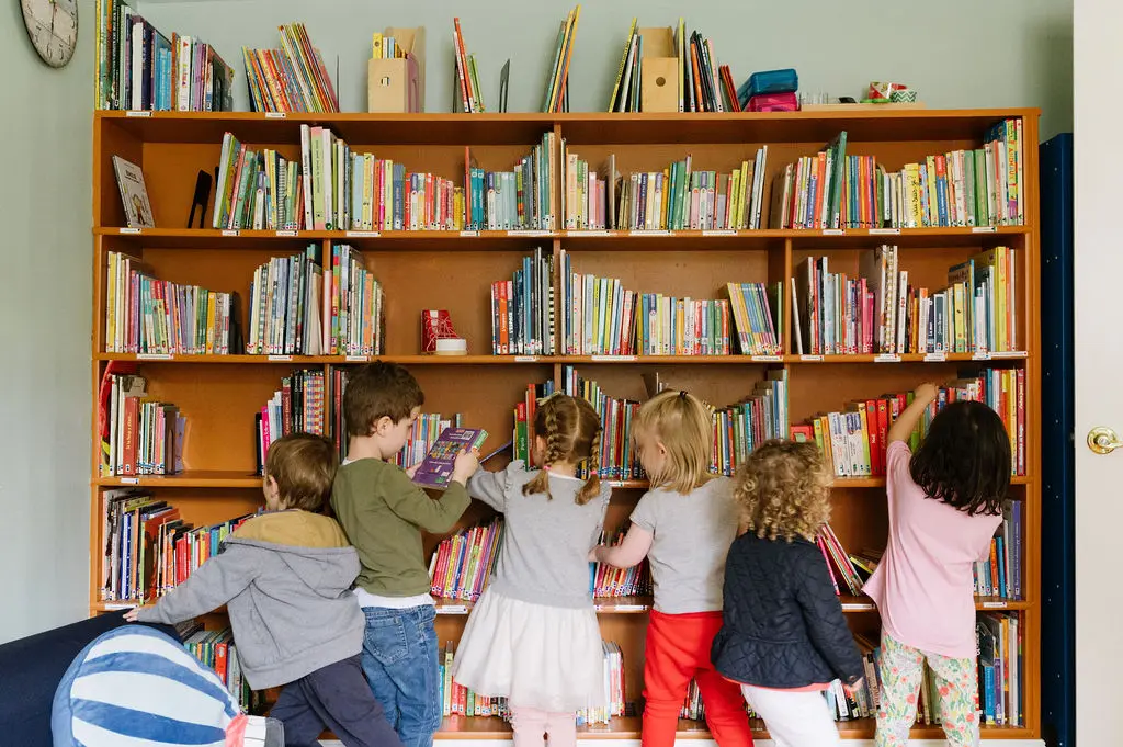Kids looking through a large bookcase at ABS French Preschool in Oakland